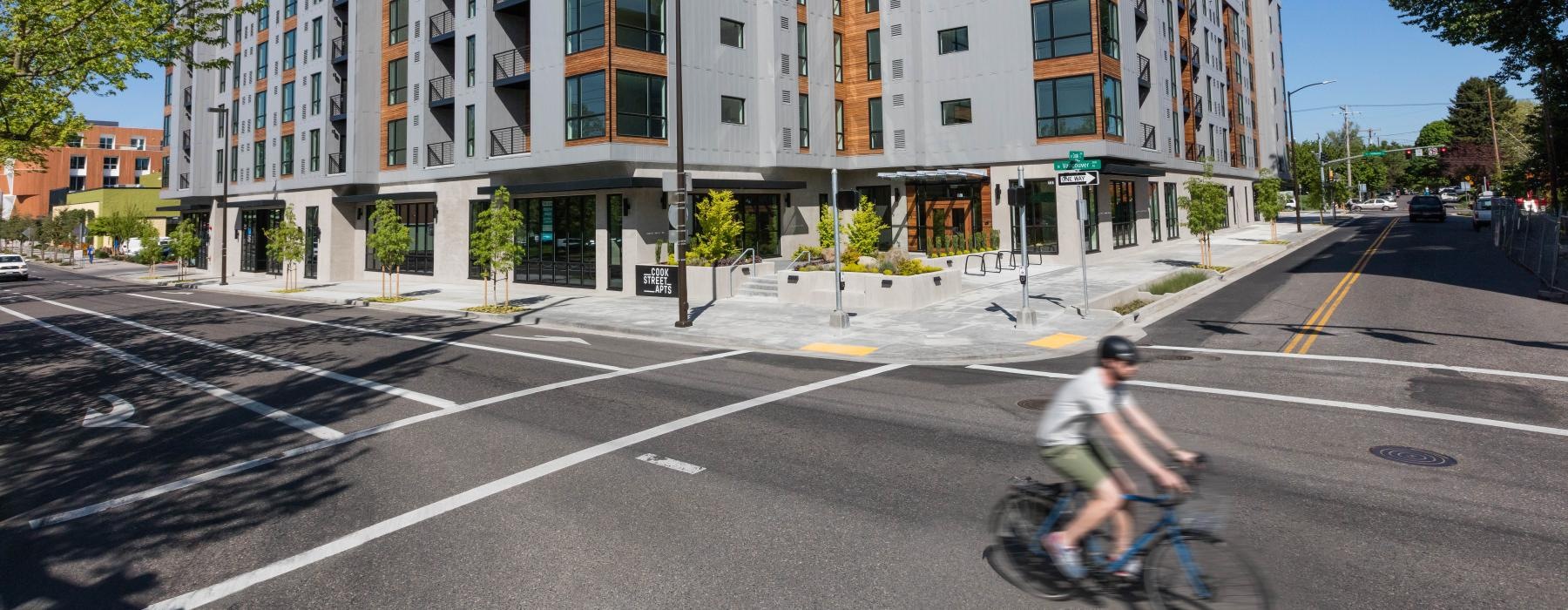 a person riding a bicycle on a street in front of a large building
