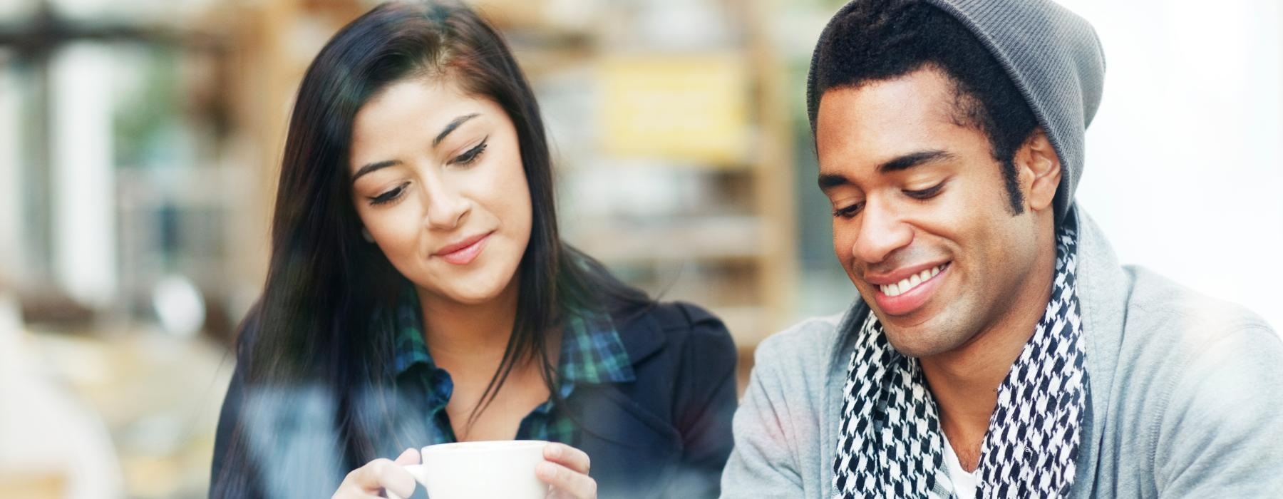 a man and a woman looking at a tablet while drinking coffee