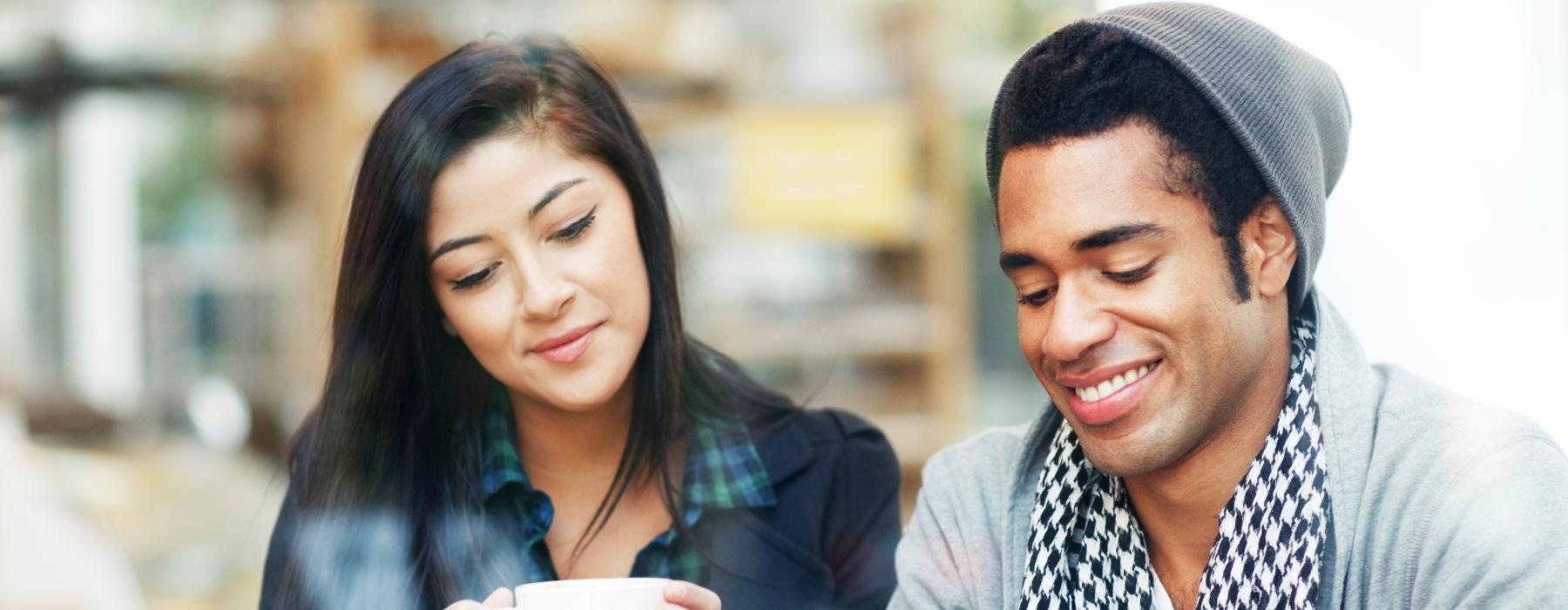 a man and a woman looking at a tablet while drinking coffee