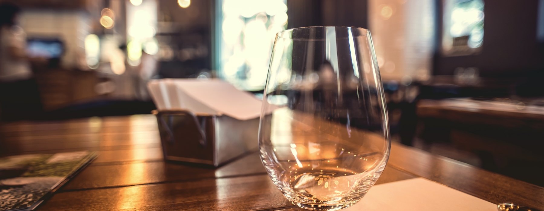 a table with an empty glass on it and a napkin holder