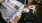 a person reading a newspaper beside coffee and a snack