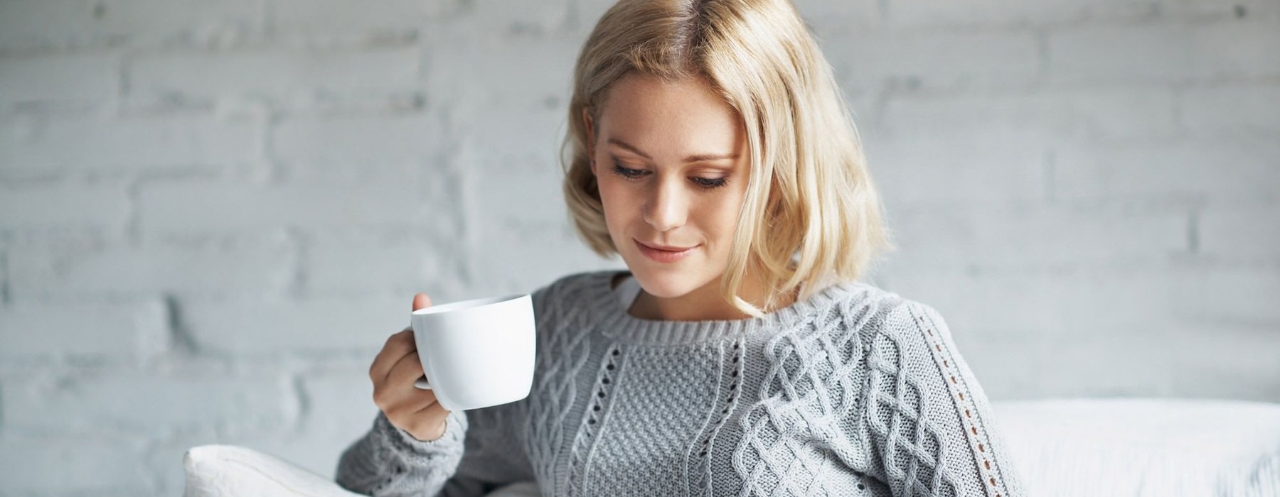 a woman sitting down holding a cup of coffee